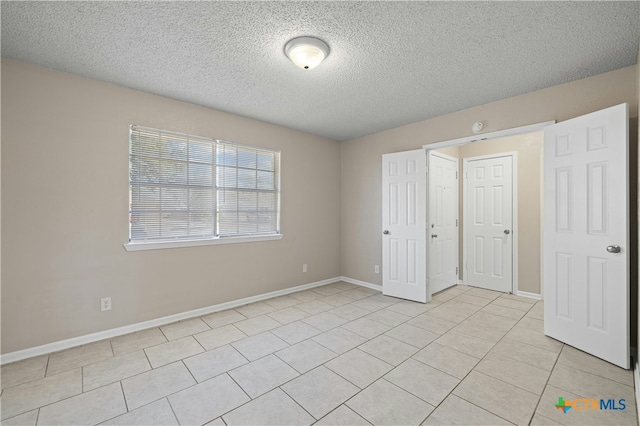 unfurnished bedroom with a textured ceiling and light tile patterned flooring