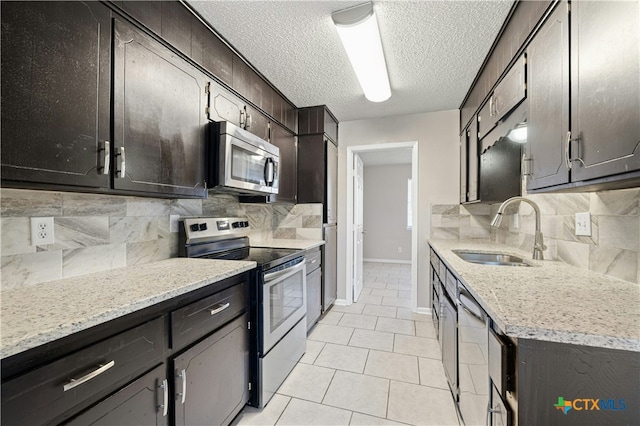 kitchen featuring stainless steel appliances, light tile patterned floors, a textured ceiling, decorative backsplash, and sink