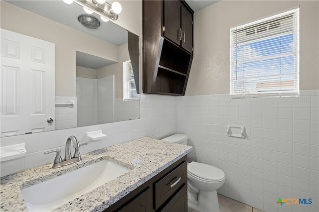 bathroom featuring tile walls, toilet, and vanity