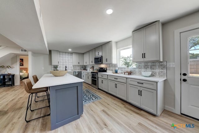 kitchen featuring a kitchen breakfast bar, gray cabinetry, and stainless steel appliances