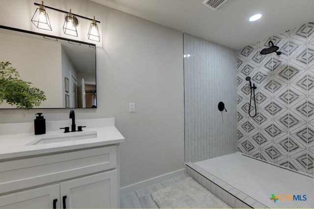 bathroom with tile patterned floors, vanity, and tiled shower