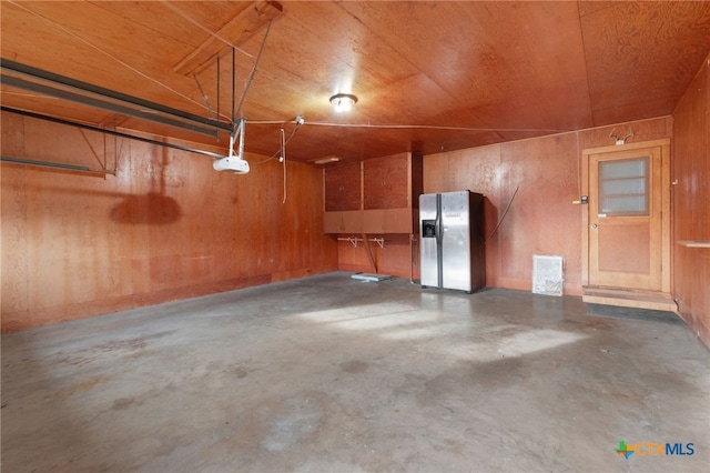 garage featuring stainless steel fridge with ice dispenser, a garage door opener, wooden walls, and wood ceiling