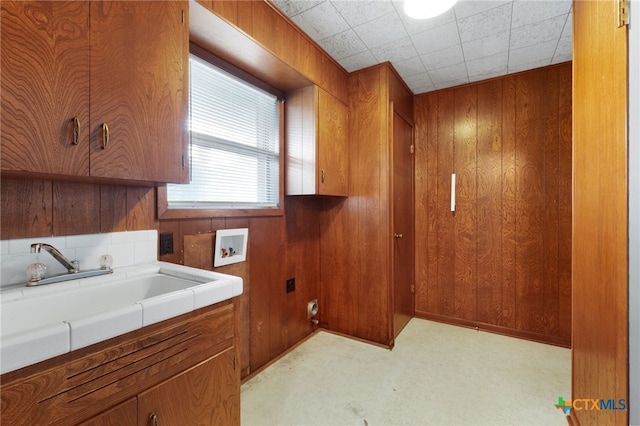 laundry area featuring cabinets, hookup for a washing machine, sink, and wood walls