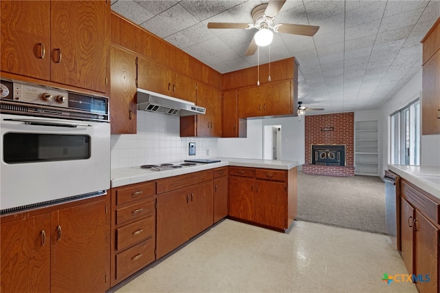 kitchen featuring kitchen peninsula, decorative backsplash, a brick fireplace, white appliances, and ceiling fan