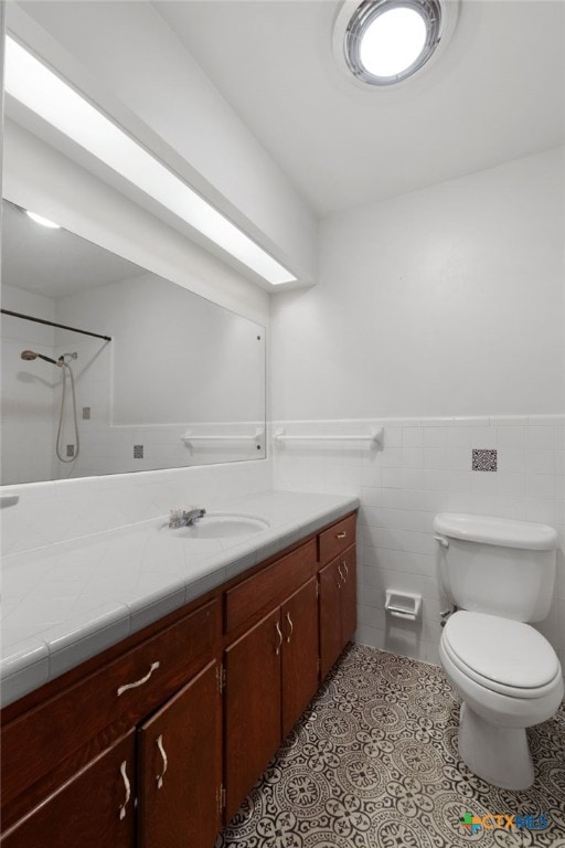 bathroom featuring tile patterned floors, vanity, toilet, and tile walls