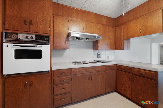 kitchen with tile countertops, decorative backsplash, and white appliances