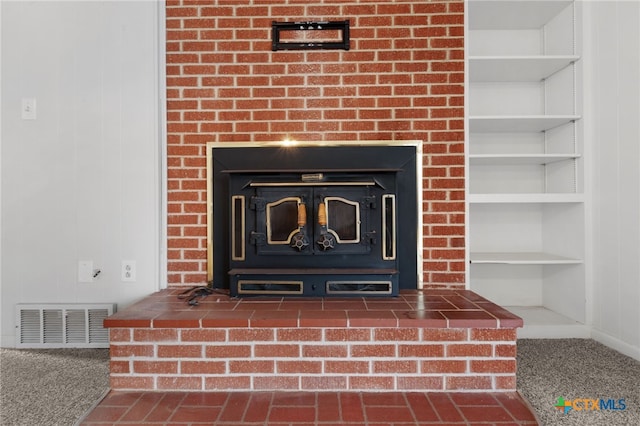 room details featuring carpet, built in shelves, and a wood stove