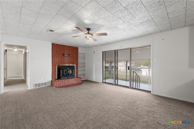 unfurnished living room featuring carpet, a wood stove, and ceiling fan