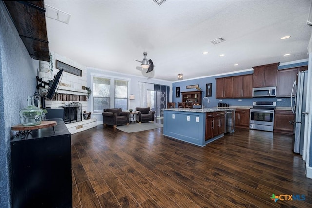 kitchen featuring visible vents, dark wood finished floors, appliances with stainless steel finishes, open floor plan, and a stone fireplace