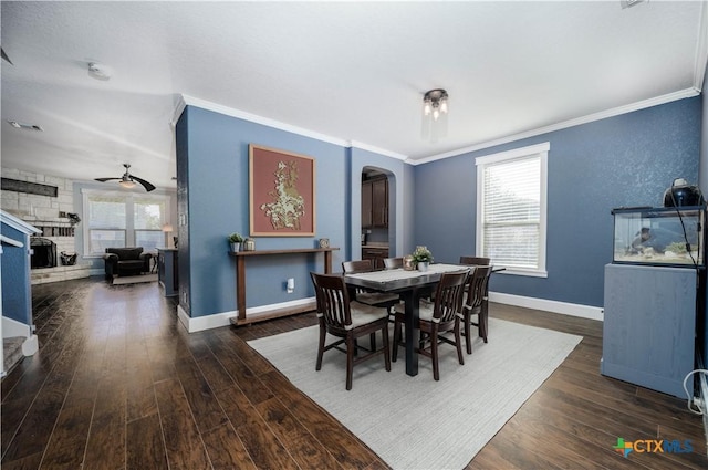 dining space with arched walkways, baseboards, wood finished floors, and a healthy amount of sunlight