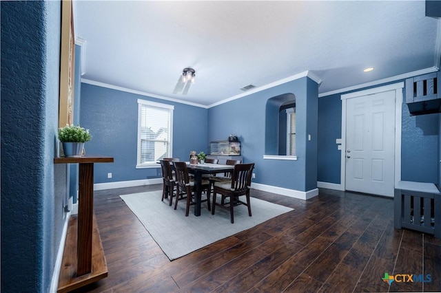 dining room with ornamental molding, visible vents, baseboards, and wood finished floors