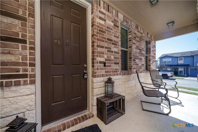 property entrance featuring covered porch and brick siding