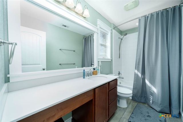 full bath featuring toilet, shower / tub combo, wood finished floors, visible vents, and vanity