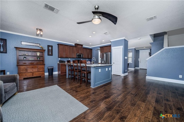 kitchen with a kitchen bar, visible vents, stainless steel appliances, and open floor plan