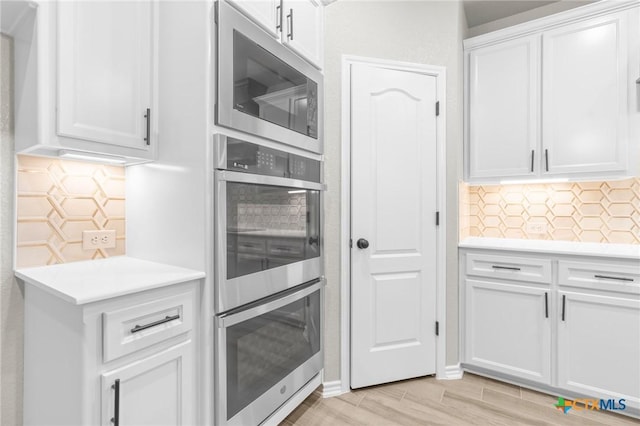 kitchen featuring white cabinetry, light wood-type flooring, tasteful backsplash, and appliances with stainless steel finishes