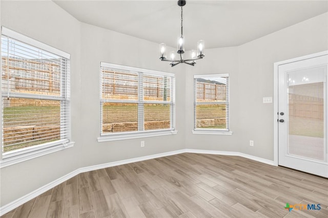 unfurnished dining area featuring an inviting chandelier and light hardwood / wood-style floors