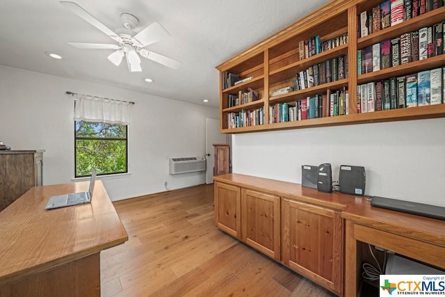 office space featuring a wall unit AC, ceiling fan, and light wood-type flooring