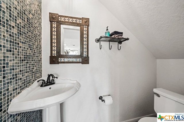 bathroom with tile walls, lofted ceiling, a textured ceiling, and toilet