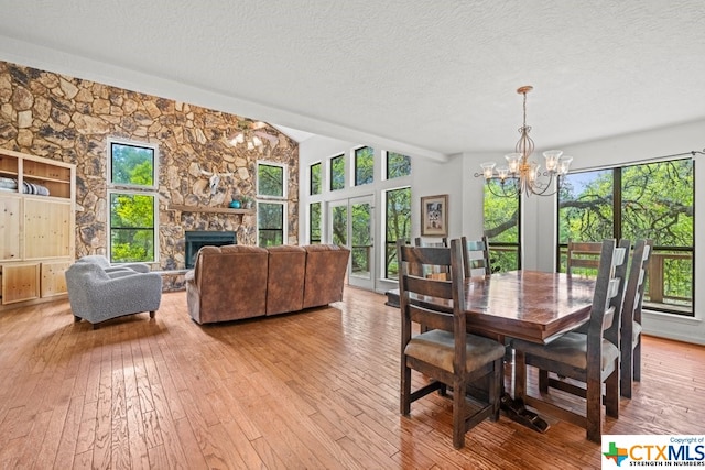 dining area featuring a stone fireplace, a wealth of natural light, and light hardwood / wood-style floors