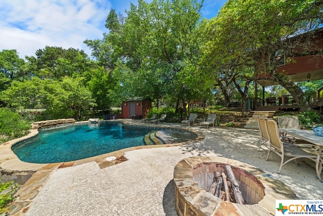 view of pool with a storage unit, a fire pit, and a patio area