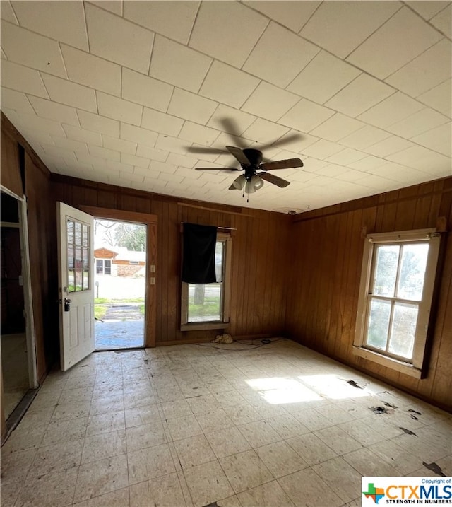 entryway with ceiling fan, a healthy amount of sunlight, and wooden walls