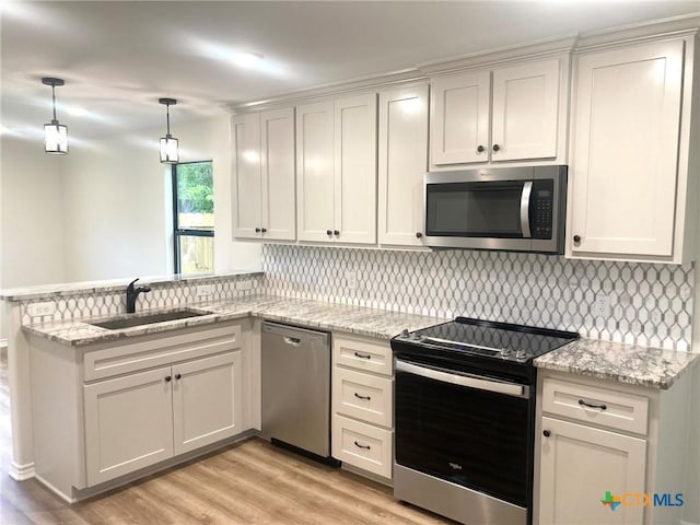 1502 Bowie Dr, Victoria, TX 77901 - kitchen with stainless steel appliances, light wood finished floors, a peninsula, and decorative backsplash