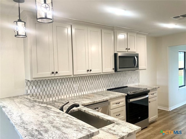 1502 Bowie Dr, Victoria, TX 77901 - kitchen featuring appliances with stainless steel finishes, a peninsula, and light stone counters