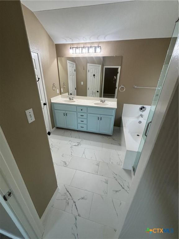 322 Lone Star Blvd, Hutto, TX 78634 - bathroom featuring marble look tiles, double vanity, and a garden tub