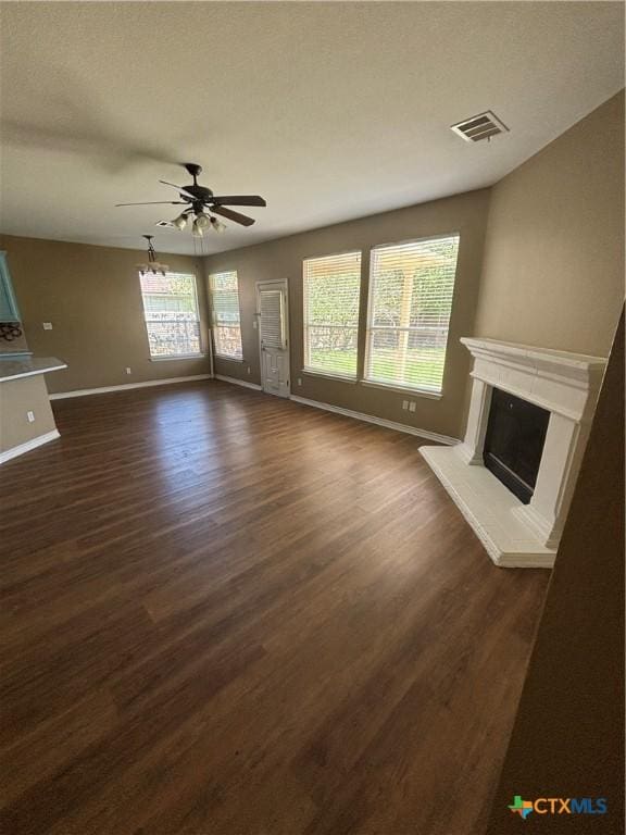 322 Lone Star Blvd, Hutto, TX 78634 - unfurnished living room featuring baseboards, dark wood-type flooring, a premium fireplace, ceiling fan, and plenty of natural light