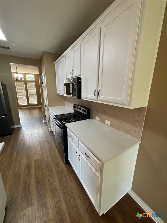 322 Lone Star Blvd, Hutto, TX 78634 - kitchen featuring black appliances, white cabinetry, dark wood-style floors, decorative backsplash, and light countertops