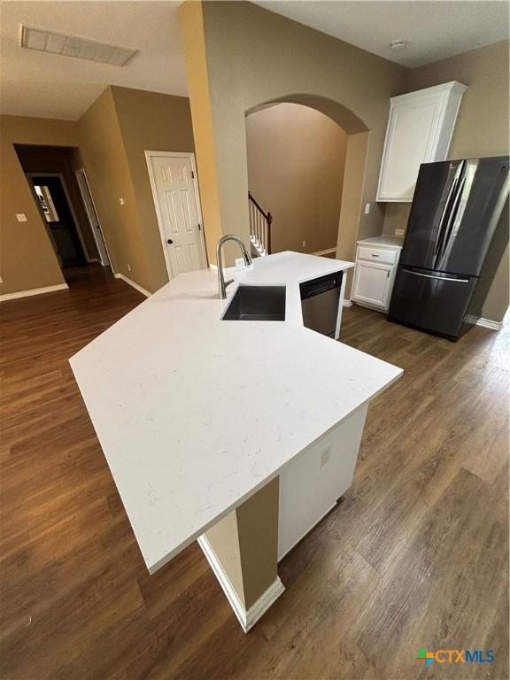 322 Lone Star Blvd, Hutto, TX 78634 - kitchen with freestanding refrigerator, a sink, arched walkways, white cabinets, and dark wood finished floors