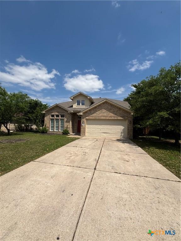 322 Lone Star Blvd, Hutto, TX 78634 - traditional-style house featuring driveway, a garage, a front lawn, and brick siding