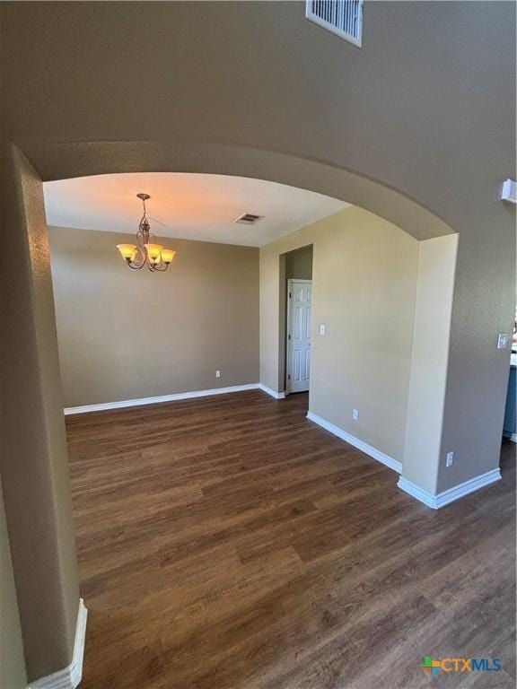 322 Lone Star Blvd, Hutto, TX 78634 - empty room featuring arched walkways, a chandelier, dark wood finished floors, and baseboards