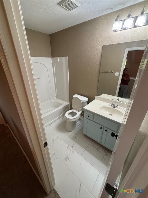 322 Lone Star Blvd, Hutto, TX 78634 - full bath featuring a textured ceiling, marble look tiles, vanity, toilet, and tub / shower combination