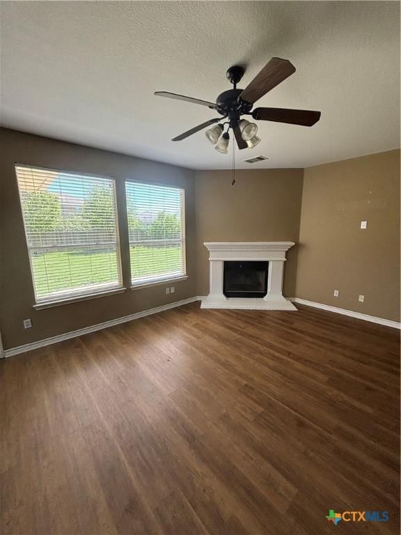 322 Lone Star Blvd, Hutto, TX 78634 - unfurnished living room with wood finished floors, baseboards, a ceiling fan, a fireplace with raised hearth, and a textured ceiling