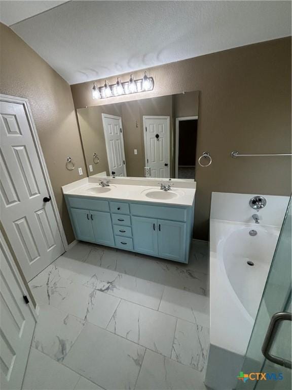 322 Lone Star Blvd, Hutto, TX 78634 - bathroom featuring marble look tiles, double vanity, a bath, a textured wall, and baseboards