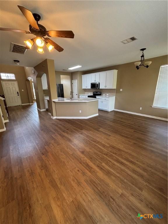322 Lone Star Blvd, Hutto, TX 78634 - unfurnished living room featuring baseboards, dark wood finished floors, a sink, a ceiling fan, and a chandelier