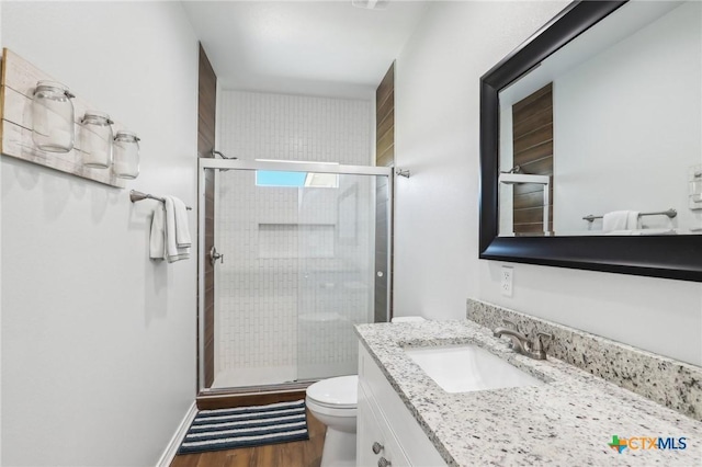 bathroom with wood-type flooring, walk in shower, vanity, and toilet