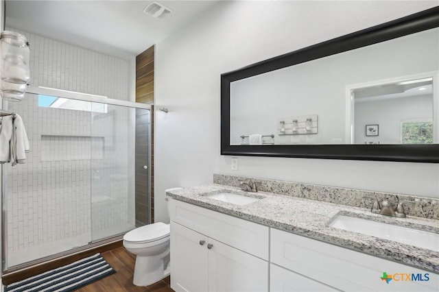 bathroom with toilet, a wealth of natural light, hardwood / wood-style floors, an enclosed shower, and vanity