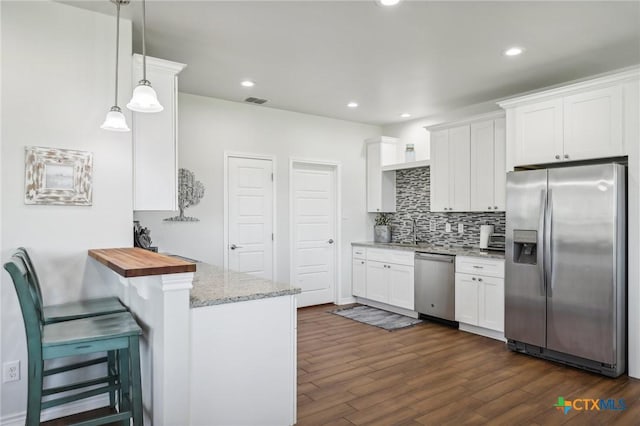 kitchen with stainless steel appliances, white cabinetry, and pendant lighting