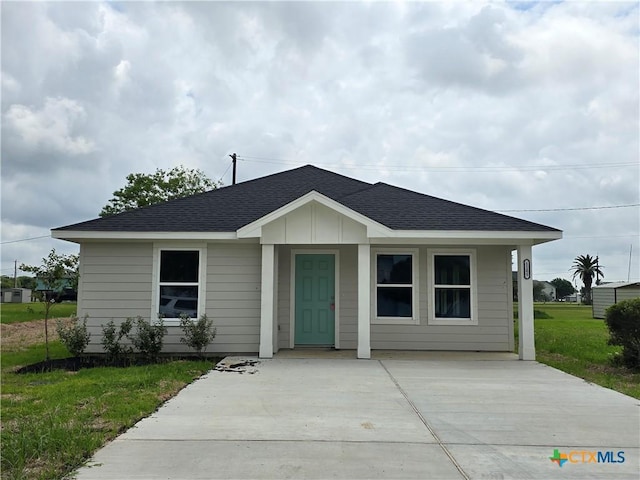 bungalow-style house with roof with shingles and a front lawn