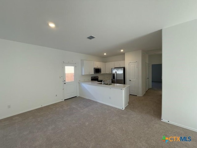 kitchen featuring kitchen peninsula, stainless steel appliances, light colored carpet, sink, and white cabinetry