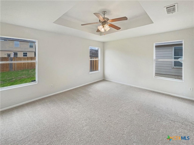 spare room featuring carpet, visible vents, and a raised ceiling