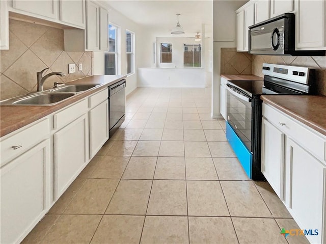 kitchen featuring stainless steel appliances, decorative backsplash, a ceiling fan, light tile patterned flooring, and a sink