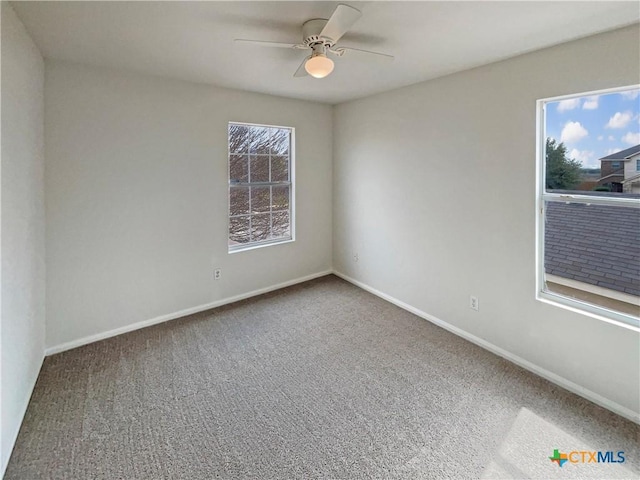 spare room featuring a ceiling fan, carpet, baseboards, and a wealth of natural light