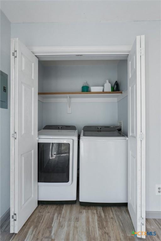 laundry area with electric panel, washer and clothes dryer, and light hardwood / wood-style flooring