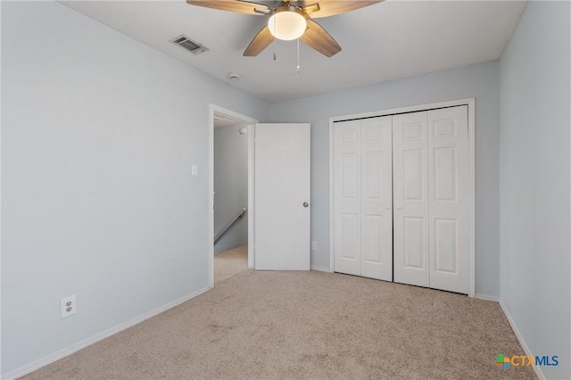 unfurnished bedroom featuring ceiling fan, a closet, and light carpet