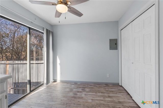 interior space featuring ceiling fan, electric panel, light hardwood / wood-style floors, and a closet