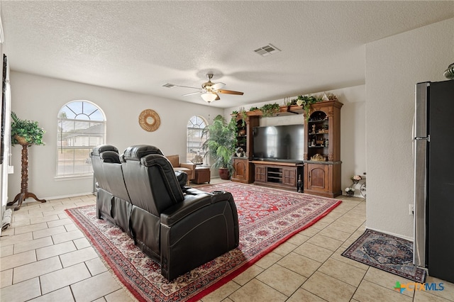 living room featuring a textured ceiling, ceiling fan, and light tile patterned flooring