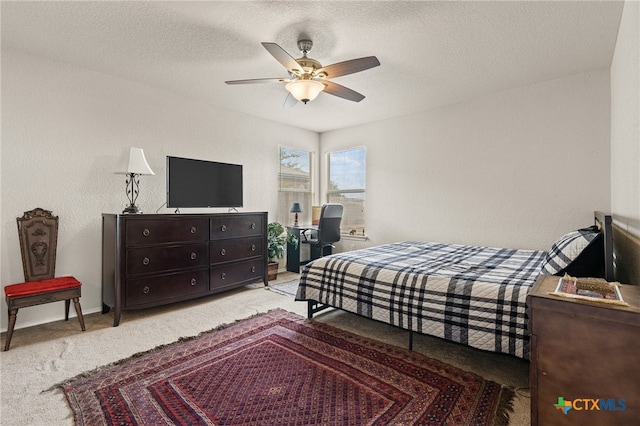 carpeted bedroom with ceiling fan and a textured ceiling